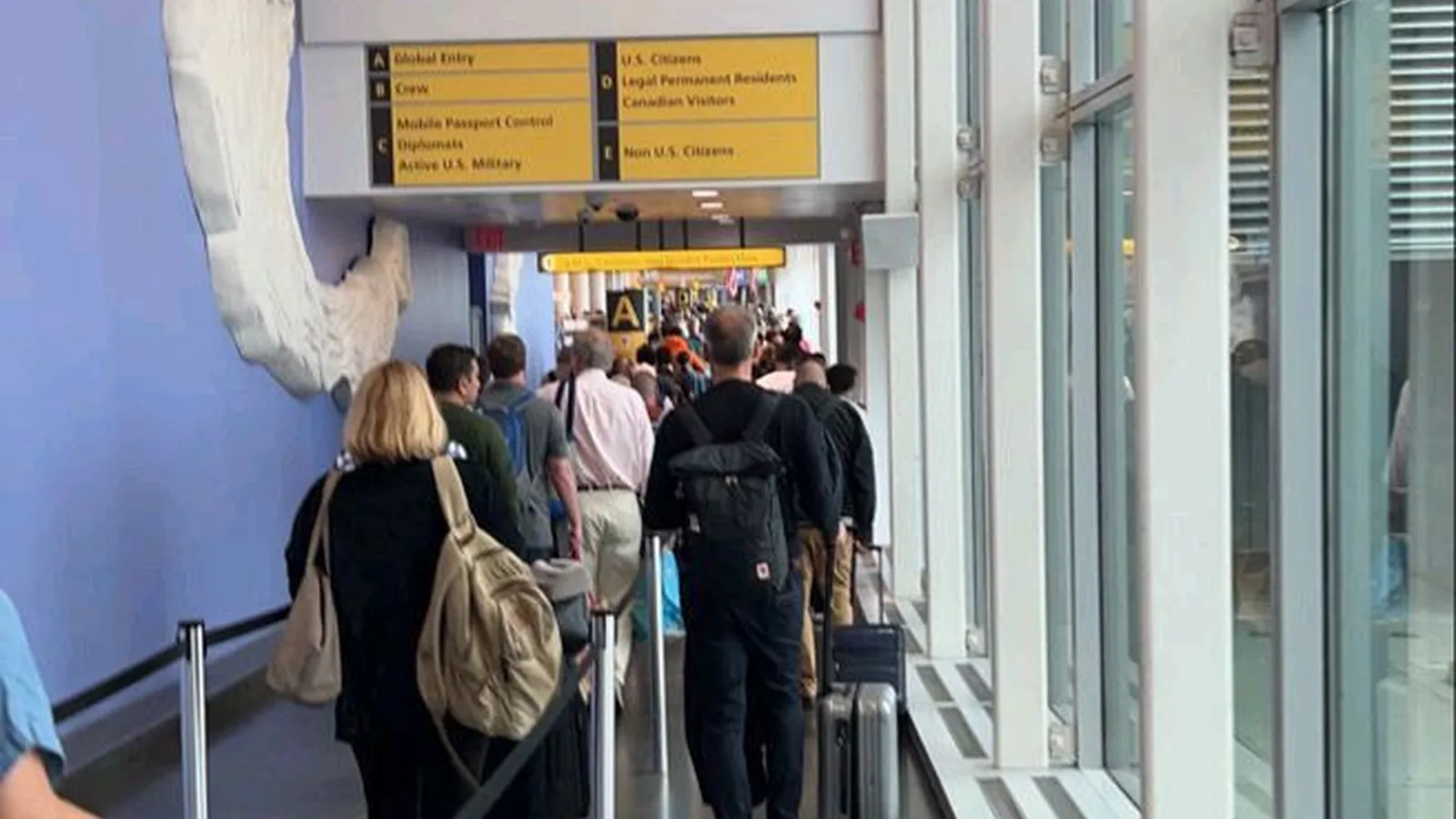 Passengers are busily leaving the airport carrying suitcases.